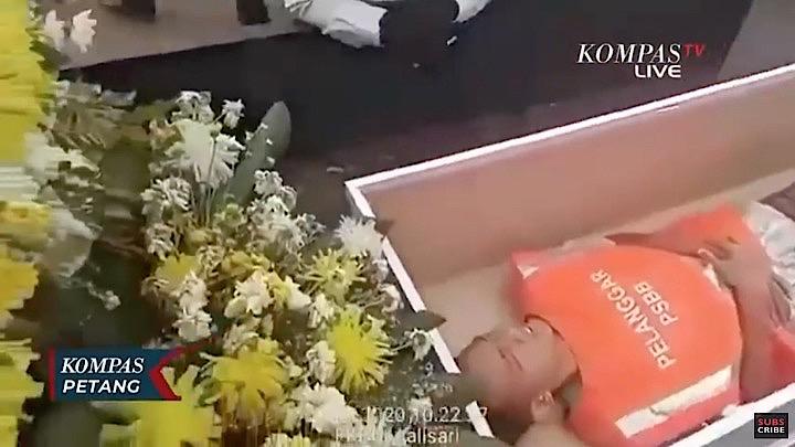 花が供えられた棺に横たわるのは公共スペースでマスクをしなかった不届き者。KOMPASTV / YouTube