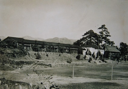 右に写る茅葺きの２階建てとその隣の西洋館が抑留所として使われた北足柄中学校（戦後間もない頃）＝北足柄小学校所蔵