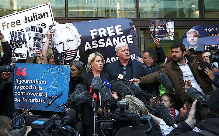 「自由な報道の擁護者」を自称するアサンジ容疑者（写真）に対して、共謀して政府機関のコンピューターに侵入し、機密文書を漏えいしたとの容疑で起訴に踏み切った米司法省の判断は、言論の自由を懸命に守ろうとする同容疑者の能力を縛るだろう、と一部の法律専門家は指摘する。写真中央の男性はウィキリークス編集長のクリスティン・フラップソン氏。ロンドンで撮影（2019年　ロイター/Hannah McKay）