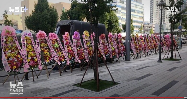 所属事務所HYBE本社前に並べられた花輪　SBS 뉴스 / YouTube