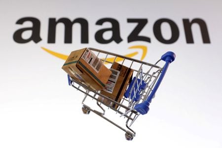 　５月１２日、米アマゾンは、大型貨物の一部配送を米物流大手フェデックスに委託したと両社が明らかにした。写真はアマゾンのロゴと買い物カートのイメージ。２月撮影（２０２５年　ロイター/Dado Ruvic）