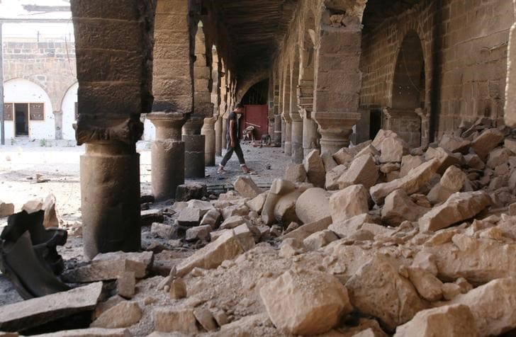 ６月１２日、シリア政権軍とイランが支援する民兵組織が、シリア南部ダルアーの反体制派が支配する地域への攻撃を強化している。写真は空爆により破壊されたモスクで瓦礫の間を歩く男性。ダルアーで９日撮影（２０１７年　ロイター／ALAA AL-FAQIR）