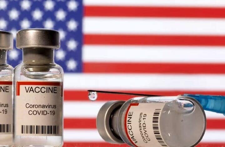 ５月１５日、米厚生省が妊婦、１０代の若者、子どもを対象とする新型コロナウイルスワクチンの定期接種の推奨を取りやめる方針だ。写真は米国の国旗と新型コロナウイルスワクチンのイメージ。２０２１年１２月撮影（２０２５年　ロイター/Dado Ruvic）