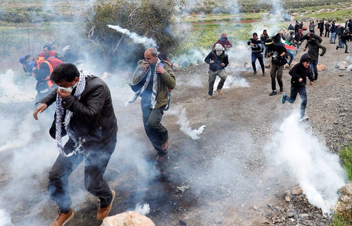 ヨルダン川西岸でイスラエル軍の催涙ガスから逃げるパレスチナ人活動家（3月29日）　Mohamad Torokman-REUTERS