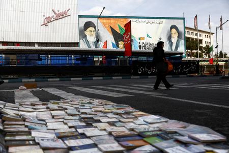3月22日、テヘランで、イスラム革命指導者のホメイニ師と前最高指導者のハメネイ師が描かれた壁画の横を歩く女性。Majid Asgaripour/WANA (West Asia News Agency) via REUTERS