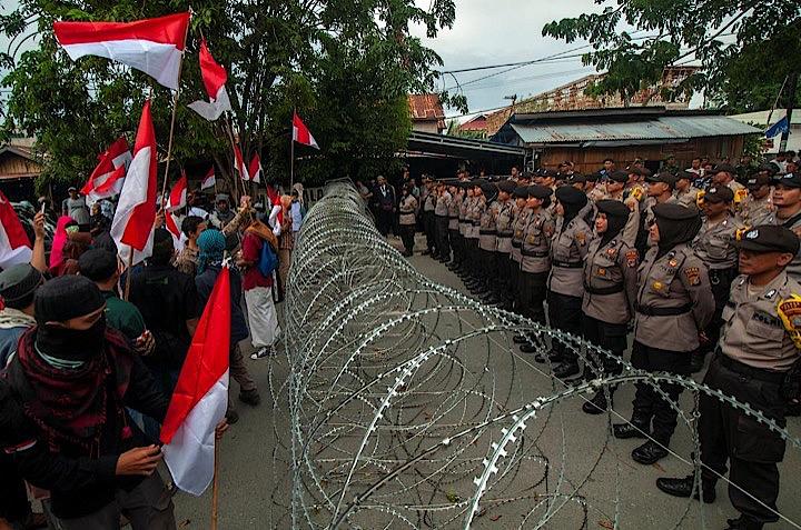 インドネシアは、大統領選の公式結果を受けて首都ジャカルタで混乱が続く中、偽情報の拡散や暴力をあおる投稿を防ぐためソーシャルメディアの利用を一部制限した。国旗を掲げスローガンを叫んで抗議活動をする人たち。パルのスラウェシ総選挙管理委員会事務所前で撮影。アンタラフォト提供（2019年　ロイター）