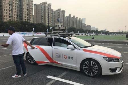 　６月４日、中国工業情報省は、自動運転車の導入を加速する計画の一環として、一定の条件下で自動運転を実現する「レベル３」のシステムを搭載した車両の公道試験を自動車メーカーなど９社に初承認したと発表した。写真は自動運転車のドアを押さえる男性。中国の上海で２０１９年８月撮影（２０２４　ロイター／Josh Horwitz）