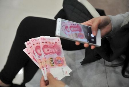 １１月１６日、中国の人民元は今後、主要通貨として存在感を高めることになるが、拙速な人民元改革は投機的な動きを誘発し、さらなる資金流出を招きかねないと警戒する向きもある。浙江省杭州の銀行で１２日撮影(２０１５年　ロイター)