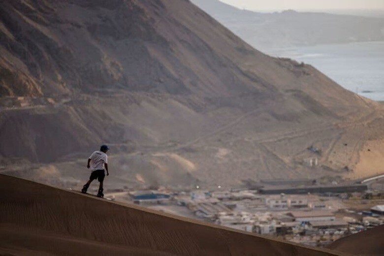 １１月１５日、南米における自然保護活動や気候変動対策資金の提供は、アマゾンの熱帯雨林など象徴的な生物多様性ホットスポットに集中し過ぎており、砂漠や湿地帯、その他の重要な生態系が危険にさらされていると、環境保護活動家や先住民リーダーらが警鐘を鳴らしている。写真はチリ・アタカマ砂漠でサンドボードを楽しむ男性。１０月２９日撮影（２０２４年　ロイター/Ivan Alvarado）