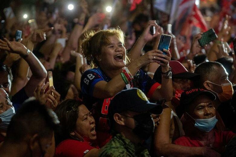 ある日曜日、マニラのアッシジ聖フランシスコ教会ではミサが行われていた。信徒たちがひざまずいて礼拝する中、司祭は、大統領選挙が安全で平穏かつ誠実なものになるよう祈りを捧げた。写真は23日、マニラで開かれた大統領選候補者の集会に参加した人々（2022年　ロイター/Lisa Marie David）