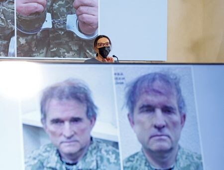 ４月１８日、ロシア国営テレビは、 ウクライナ軍と共に南東部マリウポリで戦闘に参加しロシア軍の「捕虜」になった英国人男性２人が、ウクライナ政府に逮捕された親ロシア派政治家と自分たちを交換するよう訴える映像を放映した。写真は４月１５日、ビクトル・メドベチュク氏の写真を背景にモスクワで記者会見する同氏の妻オクサナ・マルチェンコ氏（２０２２年　ロイター／Maxim Shemetov）