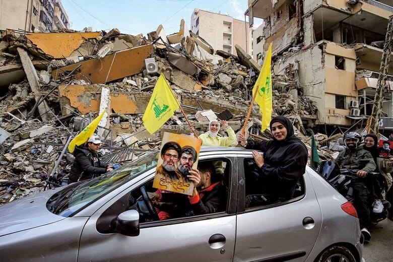 殺された指導者の写真を掲げてベイルート南郊の瓦礫の街を走るヒズボラ支持者の車　MARWAN NAAMANIｰDPAｰREUTERS