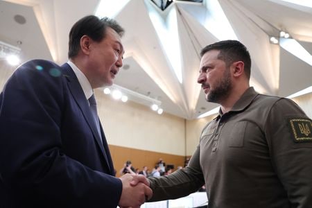 ウクライナのゼレンスキー大統領は３０日付の韓国紙・朝鮮日報のインタビューで、ロシア軍の攻撃から国を守るため、韓国による防空システムなど防衛装備品の供与を「切望」していると訴えた。写真は広島で開催されたG7首脳会議で握手を交わすウクライナと韓国首脳で２１日撮影。聯合ニュース提供（２０２３年　ロイター）
