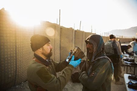 　８月２０日、タリバンがアフガニスタンの実権を握り、扱いに注意を要するデータを手中に収めるのではないかとの懸念が生じている。写真は２０１４年１２月、アフガニスタン東部ラグマーン州の前方作戦基地付近で、地元住民の生体認証データを採取するコントラクター（２０２１年　ロイター/Lucas Jackson）
