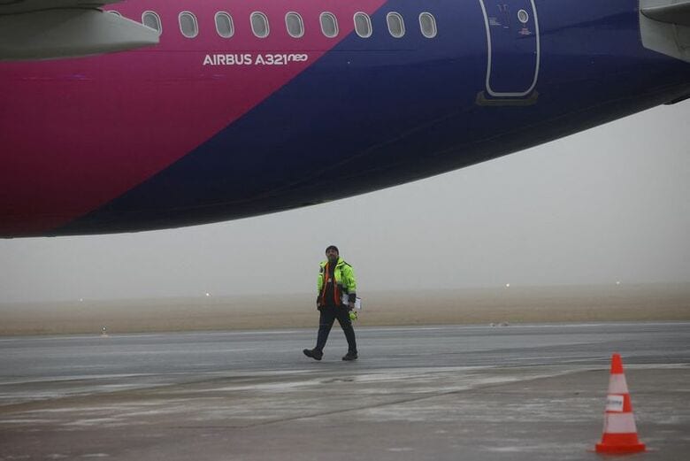 2025年12月1日、ポーランドのモドリンで、エアバスの「Ａ３２１ｎｅｏ」の機体の前を歩くスタッフ。 REUTERS/Kacper Pempel/File Photo