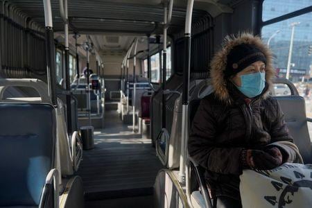 ２月１６日、中国保健当局は新型コロナウイルスについて、１５日時点で中国本土での感染による死者数は前日から１４２人増加し、１６６５人になったと発表した。写真は１５日、北京でバスに乗る女性（２０２０年　ロイター）