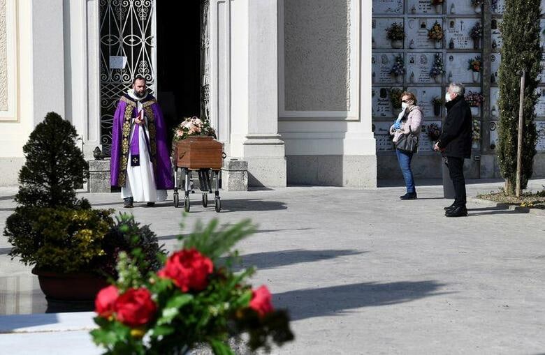 イタリアでは28日、新型コロナウイルス感染症による死者が1万人を突破した。世界全体では3万人を超えた。写真はマスクをして葬儀に参列する人たち。ロンバルディア州セリアテで撮影。（2020年　ロイター/Flavio Lo Scalzo）