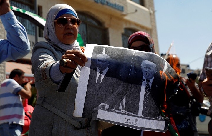 トランプとイスラエルのネタニヤフ首相の写真を燃やして援助打ち切りに抗議するパレスチナ人女性（9月8日、ヨルダン川西岸のラマラ）