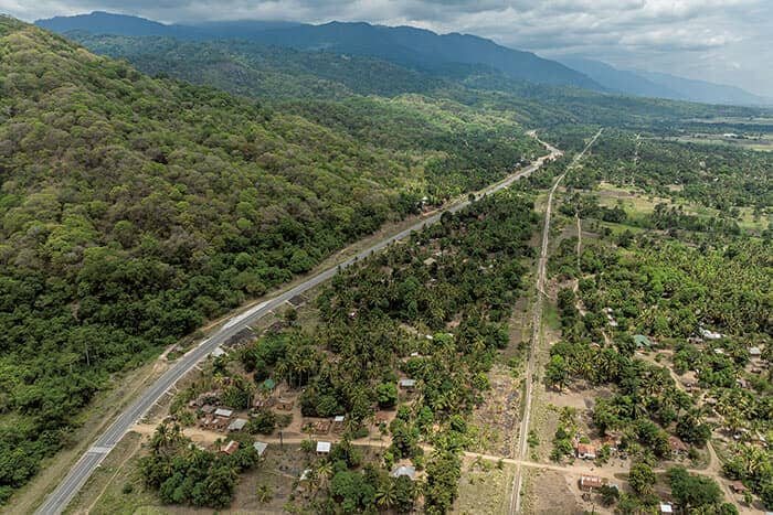 キベレッジ村近くのアスファルト道路によって、ウズングワ山脈と、耕作地や居住地とが隔てられている。道路に沿って走るのは、中国の出資などで1970年代に完成したタンザン鉄道<br>