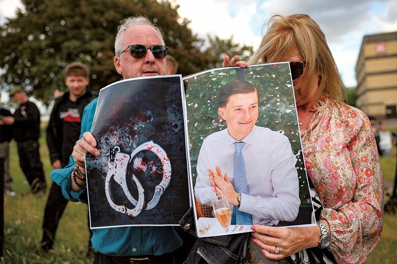 被害者のノワクと彼にかけられた手錠の写真を掲げるデモ参加者（6月2日）　ISABEL INFANTES-REUTERS