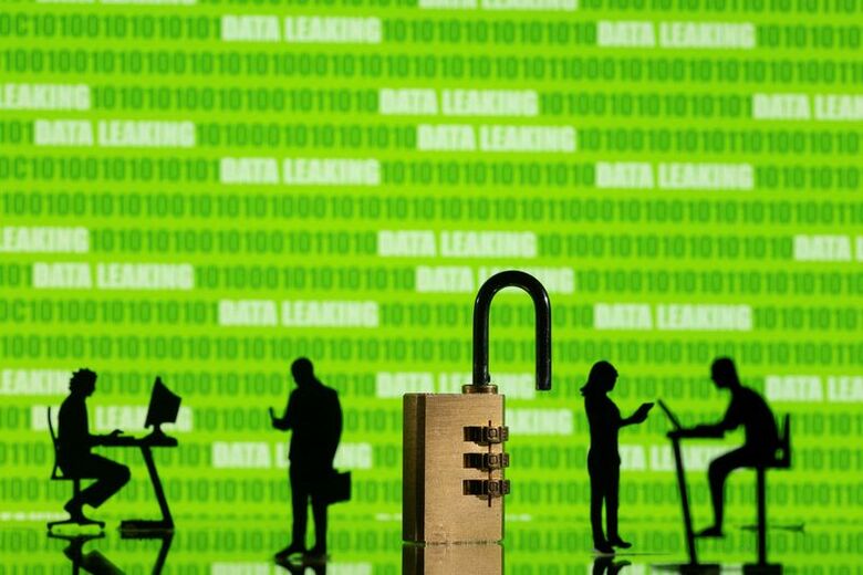 写真はバイナリーコードと「データ漏洩」の文字、パソコンを操作する人々と南京錠のイメージ。2022年2月撮影。REUTERS/Dado Ruvic