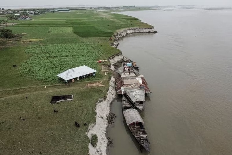 曇天の朝、農民のヌルン・ナビさん（５０）は竹の棒とトタン板を木製のボートに積み込んでいた。写真は家の屋根を舟へ運ぶ人々。１０月、クリグラムのブラマプトラ川上空からドローン撮影。（２０２５年　ロイター/Sam Jahan）