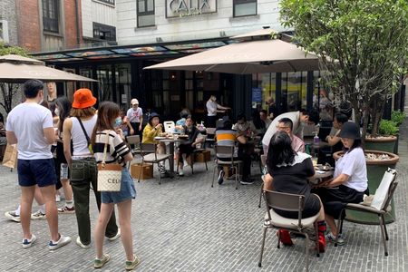 ６月２９日、 中国の上海市でレストランの店内での飲食が再開された。写真は３日、上海の飲食店のテラス席で食事する人々（２０２２年　ロイター/Xihao Jiang）
