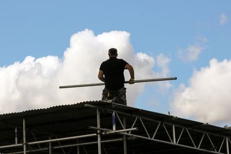 　Ｓ＆Ｐグローバルがまとめた７月の英建設業購買担当者景気指数（ＰＭＩ）は４４．３と、前月の４８．８から低下し、２０２０年５月以来の低水準となった。写真は屋根の上で作業する建設作業員。２０２０年８月、ロンドンで撮影（２０２５年　ロイター/Kevin Coombs）