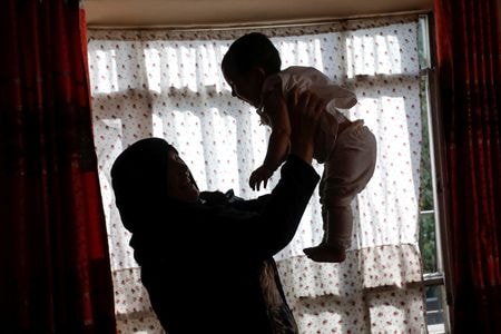 　８月９日、アフガニスタンのモネサ・ムバレズさんは、２０年にわたる民主政権下で獲得した女性の権利をやすやすと手放すつもりはない。写真は４日、カブールの自宅で孫をあやすグレスタン・サファリさん（２０２２年　ロイター/Ali Khara）