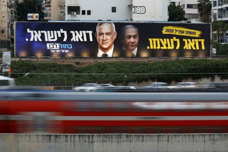 イスラエルのネタニヤフ首相と最大野党を率いるベニー・ガンツ元参謀総長は20日、挙国一致内閣を成立させることに合意した。今後18カ月間ネタニヤフ氏が続投し、その後ガンツ氏が首相に就任する。写真はガンツ氏（左）とネタニヤフが写る選挙の看板。2月18日、テルアビブで撮影（2020年　ロイターAmir Cohen）