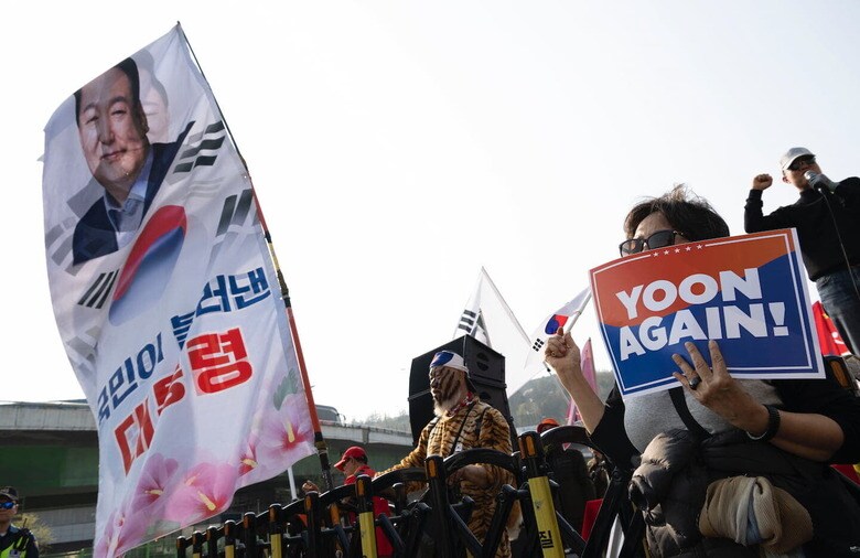 官邸を去るユン前大統領へ「ユン・アゲイン！」と書いたプラカードを掲げる保守系の市民たち　Matrix Images/Paul. J via Reuters Connect