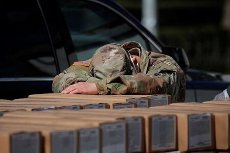 　４月３日、豪政府のチーフメディカルオフィサーを務めるブレンダン・マーフィー氏は、新型コロナウイルスの感染者が実際には世界で５００万─１０００万人に達している可能性があると語った。写真は米ニューヨークで、イースト・ハーレムの住民に配られる食事が入った箱にもたれて休憩をとる州兵。１日撮影（２０２０年　ロイター/Brendan Mcdermid）