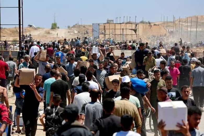 イスラエルは２６日、パレスチナ自治区ガザで支援物資の空中投下を再開したと明らかにした。写真は５月、ガザで支援物資を運ぶ人々（２０２５年　ロイター/Ramadan Abed）