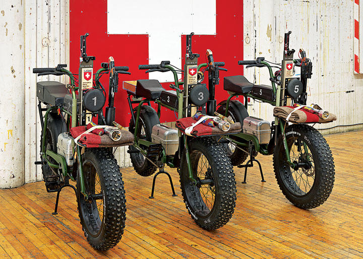 『ザ・パック』スイスの旗の前に並ぶ3台のオートバイはバチカンとローマ法王を警護するスイス衛兵隊を象徴　(c)TOM SACHS, PHOTO BY GENEVIEVE HANSON, COURTESY TOM SACHS STUDIO AND VITO SCHNABEL GALLERY