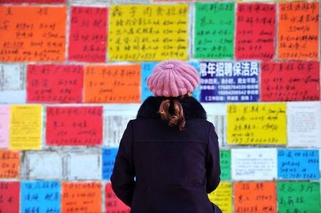 　１２月２４日、中国国務院（内閣に相当）は、雇用のさらなる促進に向けた指針を発表した。写真は山東省の青島西海岸経済新区で求人の張り紙を見る女性。１月１７日撮影（２０１９年　ロイター）