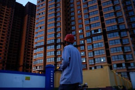 　中国南部の恵州市で金融関係の仕事を失ったレイ・ジャオユさん（３８）は今、住宅ローンの返済が滞っており、取立人に追い回される境遇にある。避けられない破局を少しでも先延ばししようと、電話には一切出ないようにしている。写真は陝西省銅川市で、まだ出来上がっていないマンションを見上げる購入者の男性。２０２３年９月撮影（２０２４年　ロイター/Tingshu Wang）
