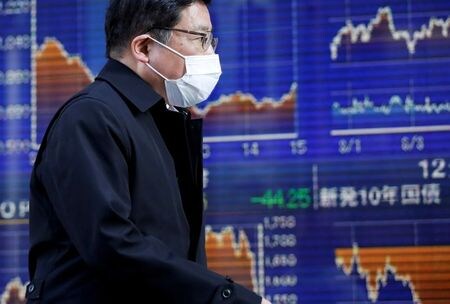 東京株式市場で日経平均は、急反発。景気敏感株を中心に幅広く物色され、前日に続いて立ち会い時間中のバブル後最高値を更新した。写真は東京にある証券会社の株価ボードの前をマスク姿で歩く通行人。今年３月に撮影。（２０２０年　ロイター／Issei Kato）