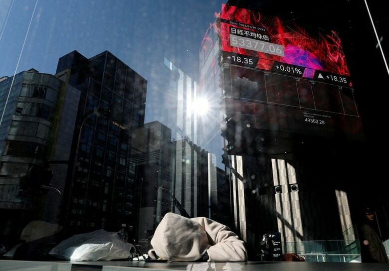 FILE PHOTO：東京の金融ビルで、日経平均株価を表示する電光掲示板の前で休む人。REUTERS/Kim Kyung-Hoon/File Photo