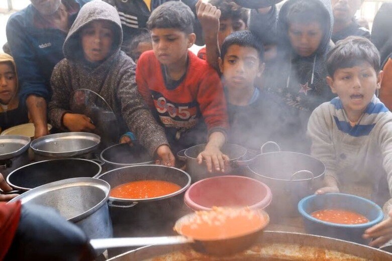 イスラエルがパレスチナ自治区ガザへの援助食料や燃料、電力などの供給を止めたことで、住民の生活に深刻な影響が生じている。写真は、食事を待つパレスチナの子どもら。３月９日、ガザ地区南部ハンユニスで撮影（２０２５年　ロイター/Hatem Khaled）