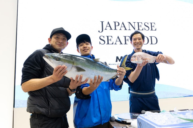 レセプションの中では、料理人と現場で活躍する漁業関係者によるトークショーも実施した。写真は、ブリ及びタイの取り扱いについて紹介する石川県輪島市の漁師の田井太也（たいたかなり）氏（中央）、同市で鮮魚店を営む中小路武士（なかしょうじたけし）氏、元公邸料理人の工藤英良（くどうえいりょう）シェフ
