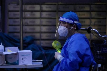 　８月１３日、中国では、南西部の主要都市・重慶市を含む複数の地域で気温が４０度を超える猛暑日となった。写真は７月、上海で携帯扇風機を使う医療従事者（２０２２年　ロイター／Aly Song）