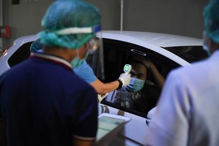 　３月２６日、タイ政府は２６日、ツイッターで、新型コロナウイルス感染者が新たに１１１人確認され、累計で１０４５人となったと明らかにした。写真はコロナウイルス感染の検査所で、体温をチェックする医療関係者。バンコクで撮影（２０２０年　ロイター／Chalinee Thirasupa）