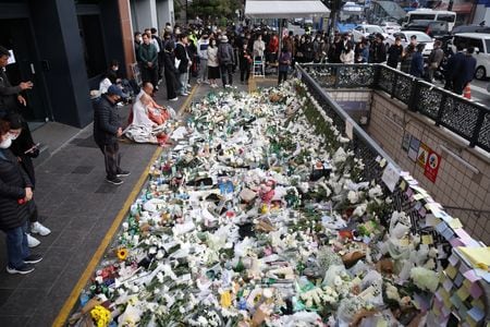 　１１月１日、韓国ソウルの繁華街で１５０人超が死亡した雑踏事故の影響で国内各地の秋の祭りやＫポップコンサートが延期になり、服喪ムードの国民も集まる予定を控えるなどし、既に減速していた経済成長にさらに下押し圧力がかかる恐れが出ている。写真は事故現場の近くで花を手向ける人々。ソウルで撮影（２０２２年　ロイター／Kim Hong-Ji ）