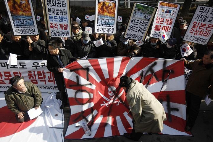 日本の歴史認識と竹島（韓国名・独島）問題に抗議する人々。旭日旗の隣では安倍晋三首相のお面をかぶった人物が正座している（2013年3月）　Kim Hong-Ji-REUTERS