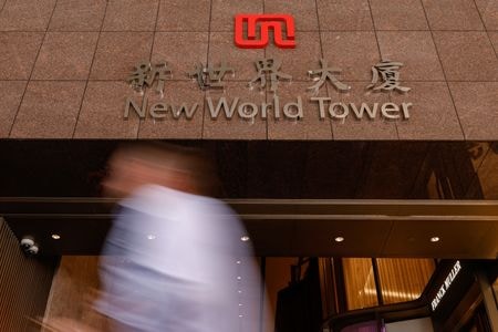 　６月２日、香港の不動産大手、新世界発展が６月に予定していた永久債の利払いを見送ると発表したことを受け、同社の資金繰りに対する懸念が強まり２日の金融市場で株価と債券価格が急落した。写真は中国・香港の新世界発展本社前を通り過ぎる男性。２０２４年９月撮影（２０２５年　ロイター/Tyrone Siu）