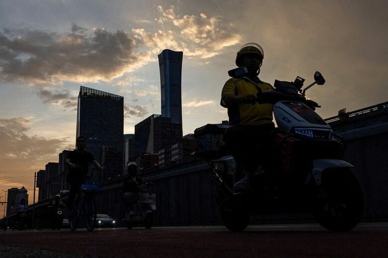 北京のビジネス地区を自転車で走る配達員。７月６日、北京で撮影。REUTERS/Maxim Shemetov