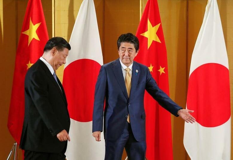 日中両政府は4月に予定されていた習近平国家主席の国賓としての訪日を延期することで事実上合意した。写真はG20大阪サミットで習氏（左）を迎える安倍晋三首相。2019年6月撮影（2020年　ロイター／代表撮影）