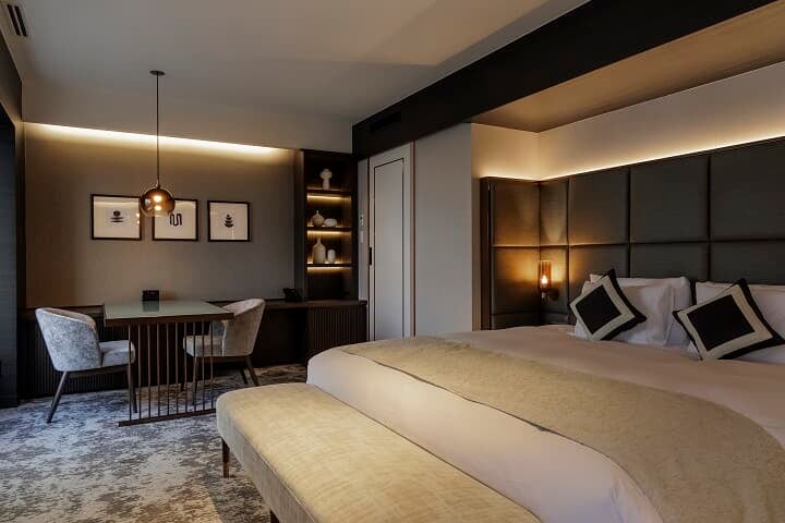 48平米の客室。部屋の中央に置かれたキングサイズのベッドは、眠りの質にこだわった高品質のものを。選び抜かれた寝具や家具など細部にこだわりを感じる。全室デスクとチェア、ソファとローテーブルが完備されており、PC作業や食事、休憩などあらゆるシーンに対応。