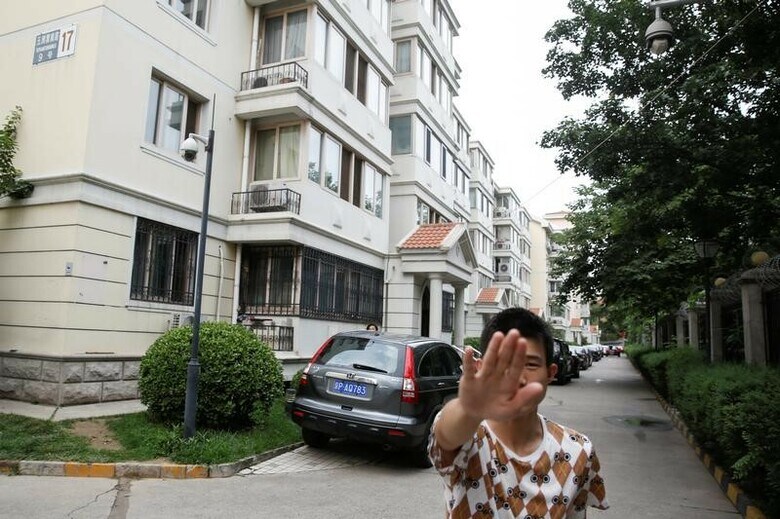 ７月、ノーベル賞受賞者の劉暁波氏の妻劉霞氏が住む北京のアパート前で、写真を撮ろうとしたカメラマンを制止する私服の治安職員（２０１７年　ロイター/Thomas Peter）