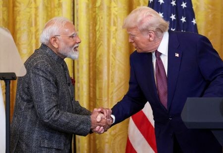 　４月１０日、インド政府高官は、米国との貿易協定締結を迅速に進めたいと述べた。写真はホワイトハウスで握手するインドのモディ首相とトランプ米大統領。２月１３日撮影（２０２５年　ロイター/Kevin Lamarque）